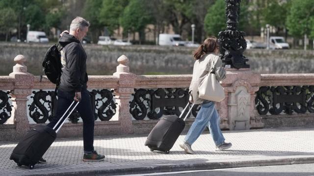 Dos turistas caminan con su maleta por el Puente de María Cristina de Donostia. / Ruben Plaza