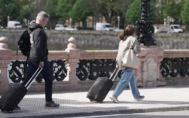 Dos turistas caminan con su maleta por el Puente de María Cristina de Donostia. / Ruben Plaza