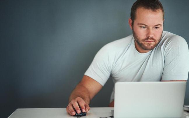 Un hombre trabaja frente a un ordenador portátil.