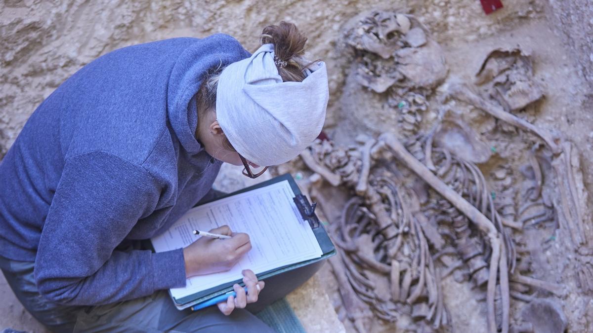 Una trabajadora anota los datos de un cuerpo en una fosa durante la presentación del hallazgo de la primera fosa común con represaliados de la Guerra Civil en el Cementerio de Osuna.