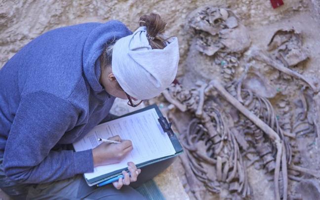 Una trabajadora anota los datos de un cuerpo en una fosa durante la presentación del hallazgo de la primera fosa común con represaliados de la Guerra Civil en el Cementerio de Osuna.