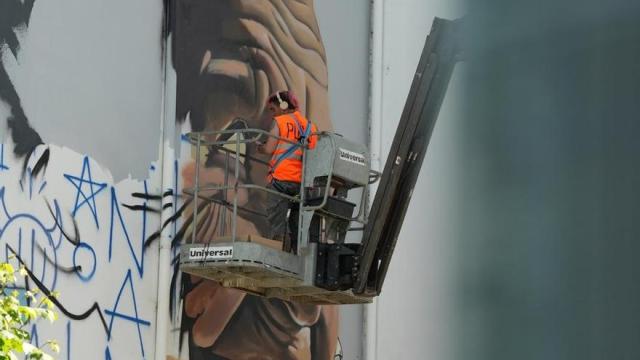 El muralista Iban Urreta trabajando en la obra que vestirá la fachada de este edificio de la calle Doctor Báñez, contigua al bar Nuevo.