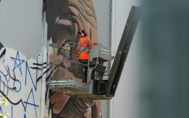 El muralista Iban Urreta trabajando en la obra que vestirá la fachada de este edificio de la calle Doctor Báñez, contigua al bar Nuevo.