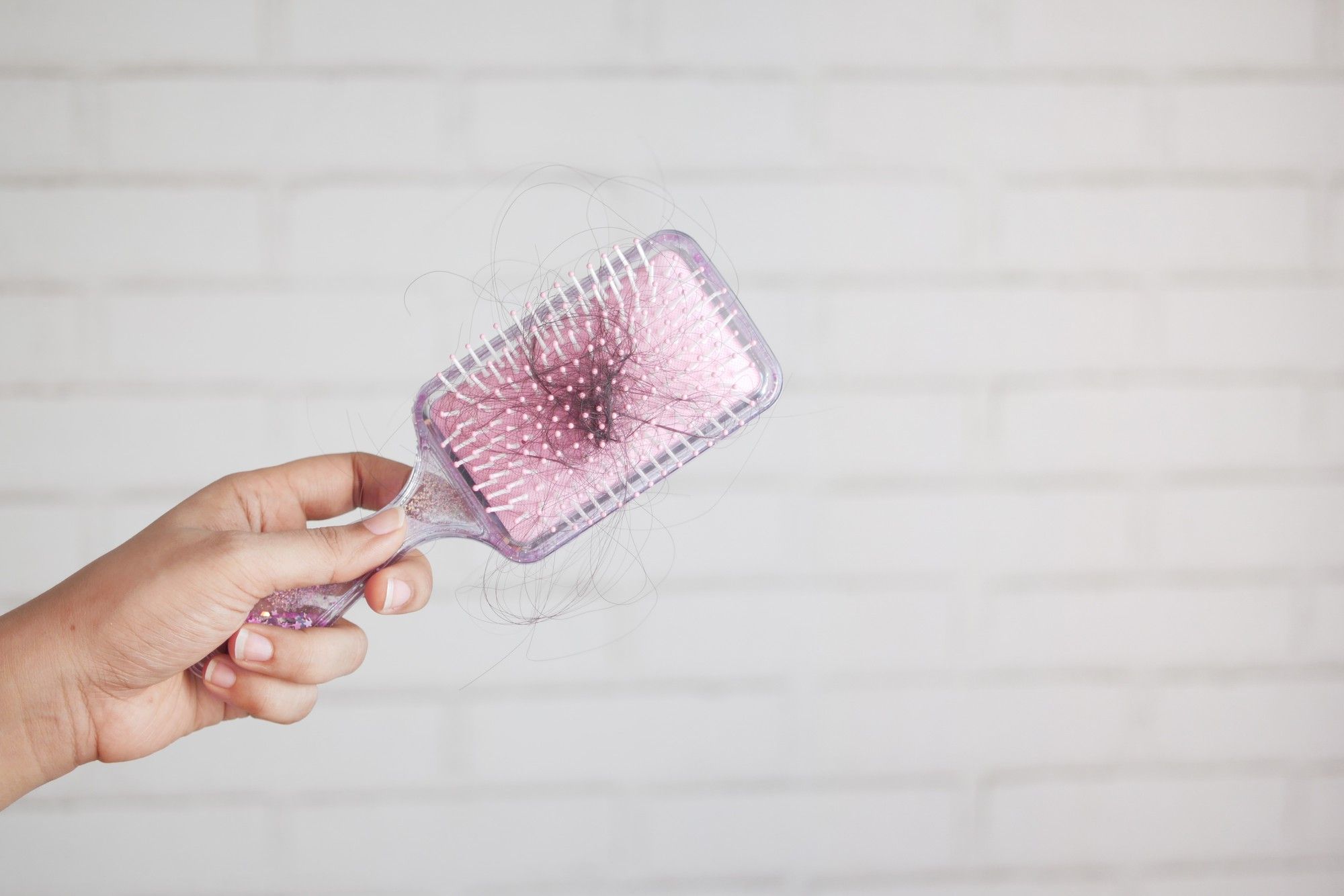 Una mujer sostiene un cepillo con pelos.