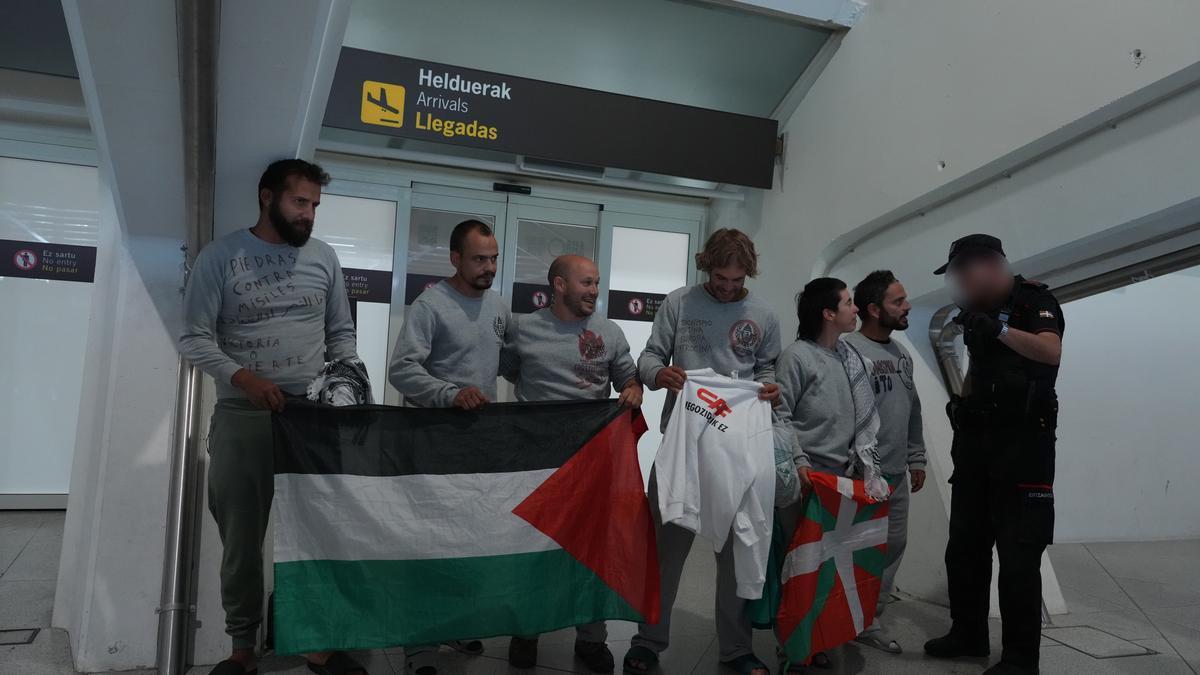 Activistas despliegan una ikurriña y una bandera palestina en el aeropuerto de Loiu.