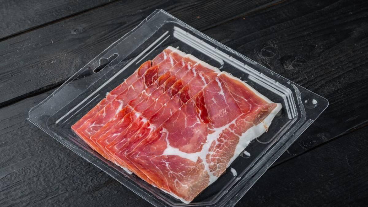 Lonchas de jamón envasado sobre un fondo de madera