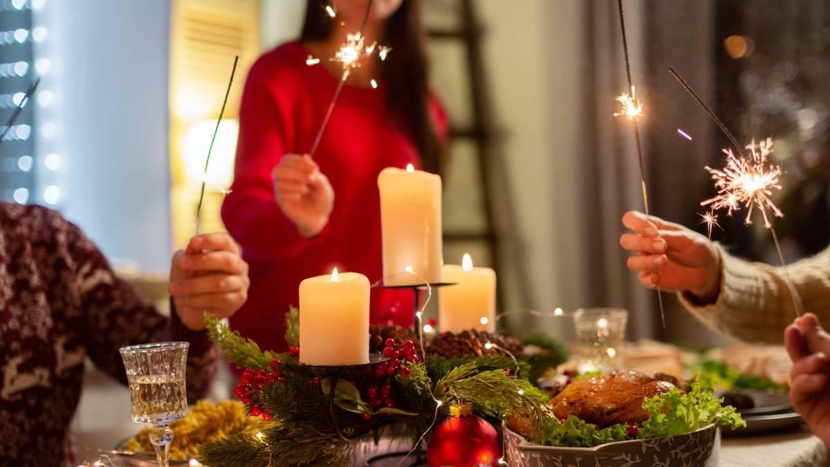 Varias personas con bengalas celebran la entrada del nuevo año alrededor de la mesa