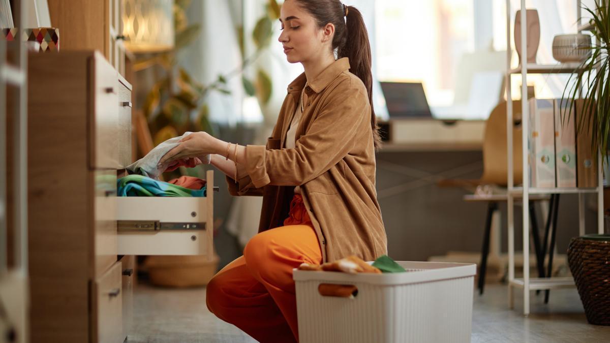 Una mujer recoge la ropa planchada en un cajón.