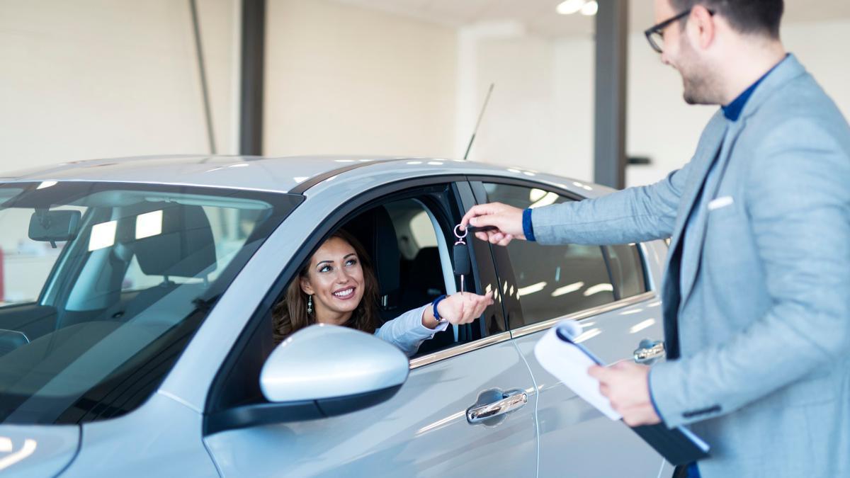 Un trabajador de un concesionario entrega las llaves de un coche a su nueva propietaria.