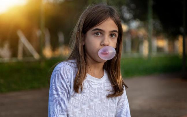 Una niña hace una bomba con un chicle.