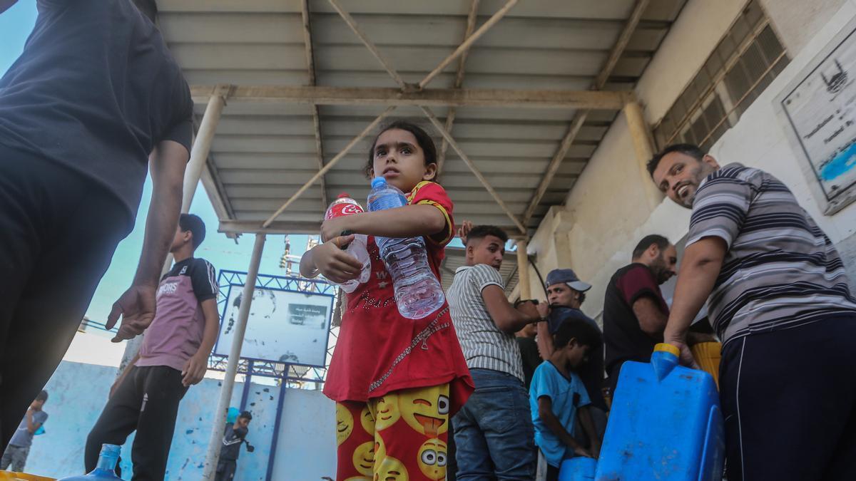 Refugiados en la ciudad del sur de Gaza de Khan Junis hacen cola para coger agua.