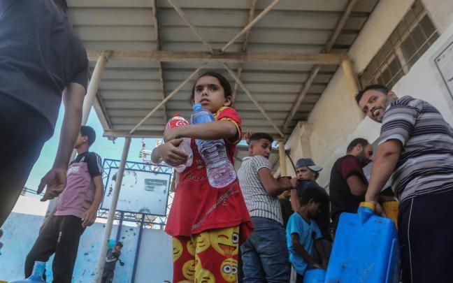 Refugiados en la ciudad del sur de Gaza de Khan Junis hacen cola para coger agua.