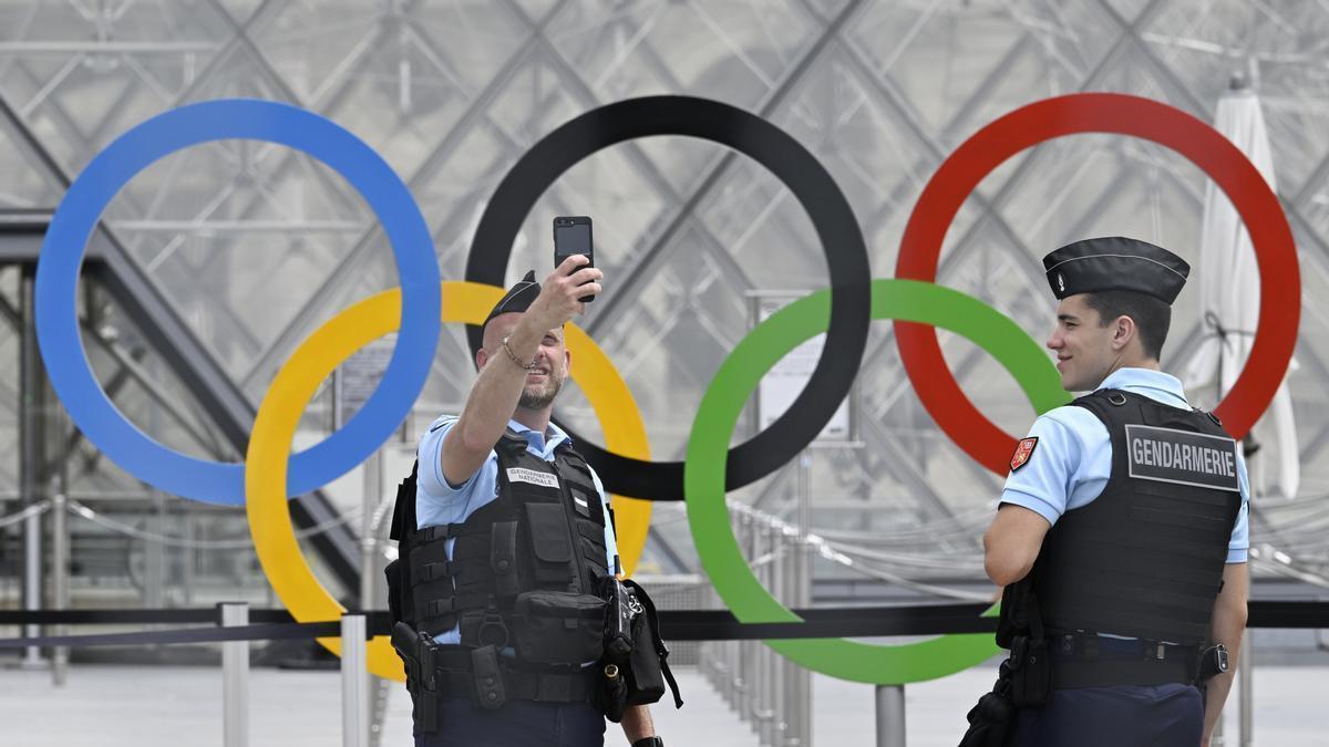 Policías franceses se sacan una foto con los aros olímpicos en el Louvre.