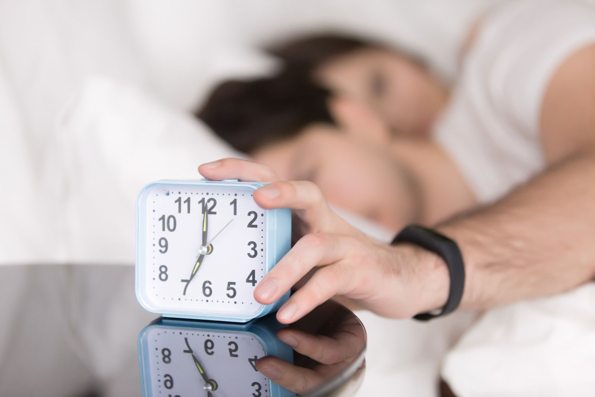 Un hombre pulsa el botón para detener la alarma del despertador.