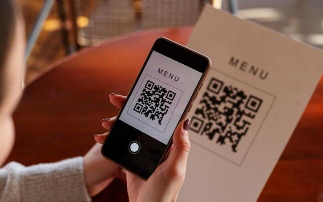 Una persona escanea un código QR en un restaurante. Una persona escanea un código QR en un restaurante.