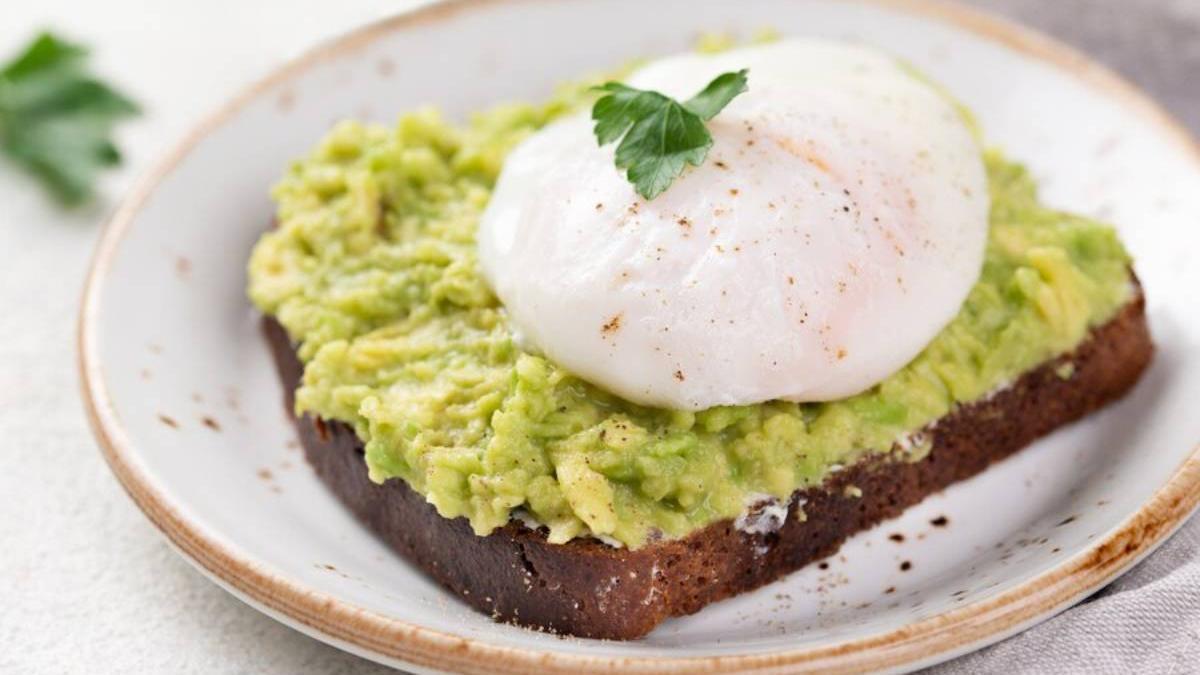 Huevo poché sobre una tostada de pan integral con guacamole.