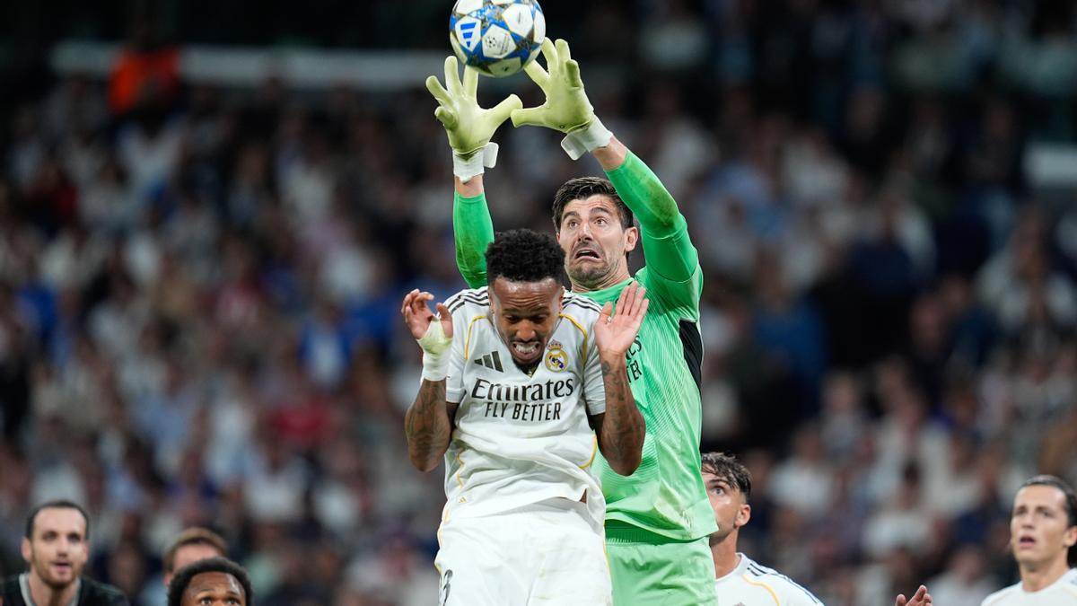 Thibaut Courtois trata de atrapar el balón en presencia de Eder Militao.