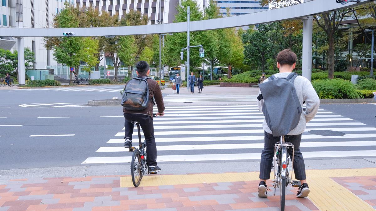 Dos jóvenes ciclistas se disponen a cruzar un paso de peatones.