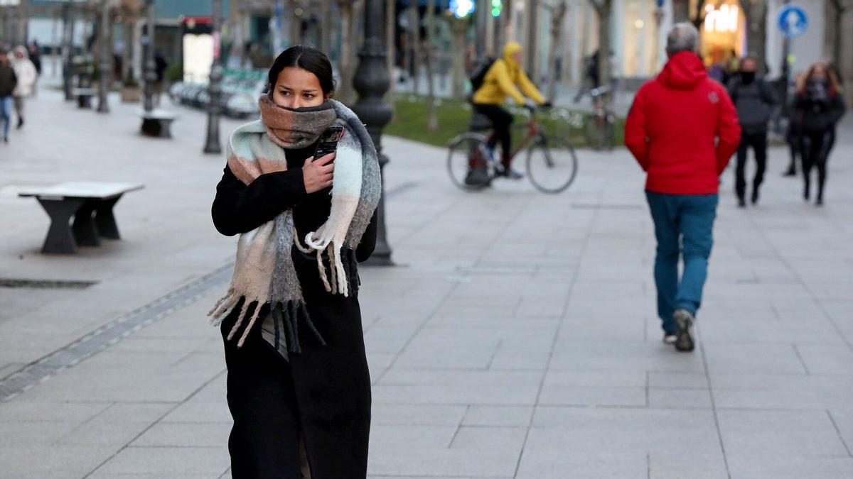 Una joven se protege con una bufanda del frío en el centro de Pamplona.