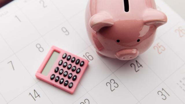 Una hucha y una calculadora sobre una hoja de calendario.
