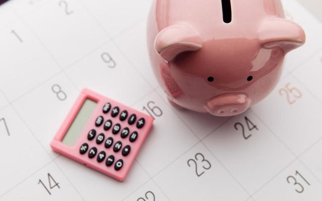 Una hucha y una calculadora sobre una hoja de calendario.