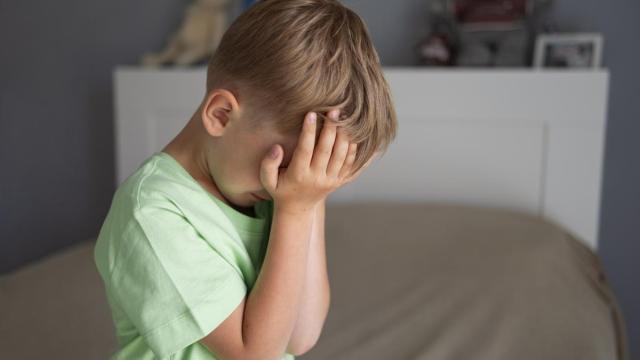 Niño se tapa la cara con las manos.