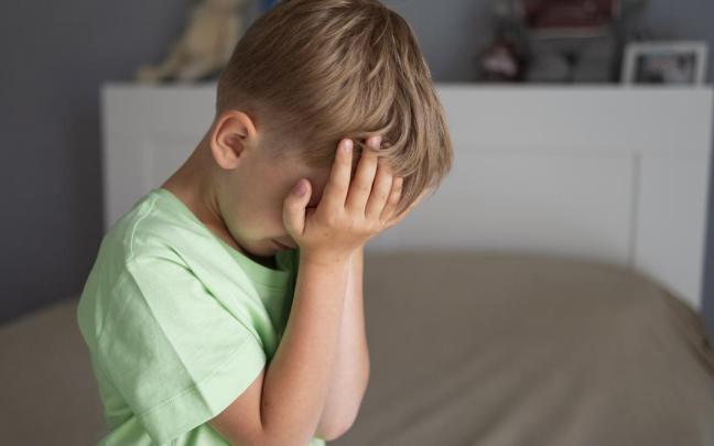 Niño se tapa la cara con las manos.