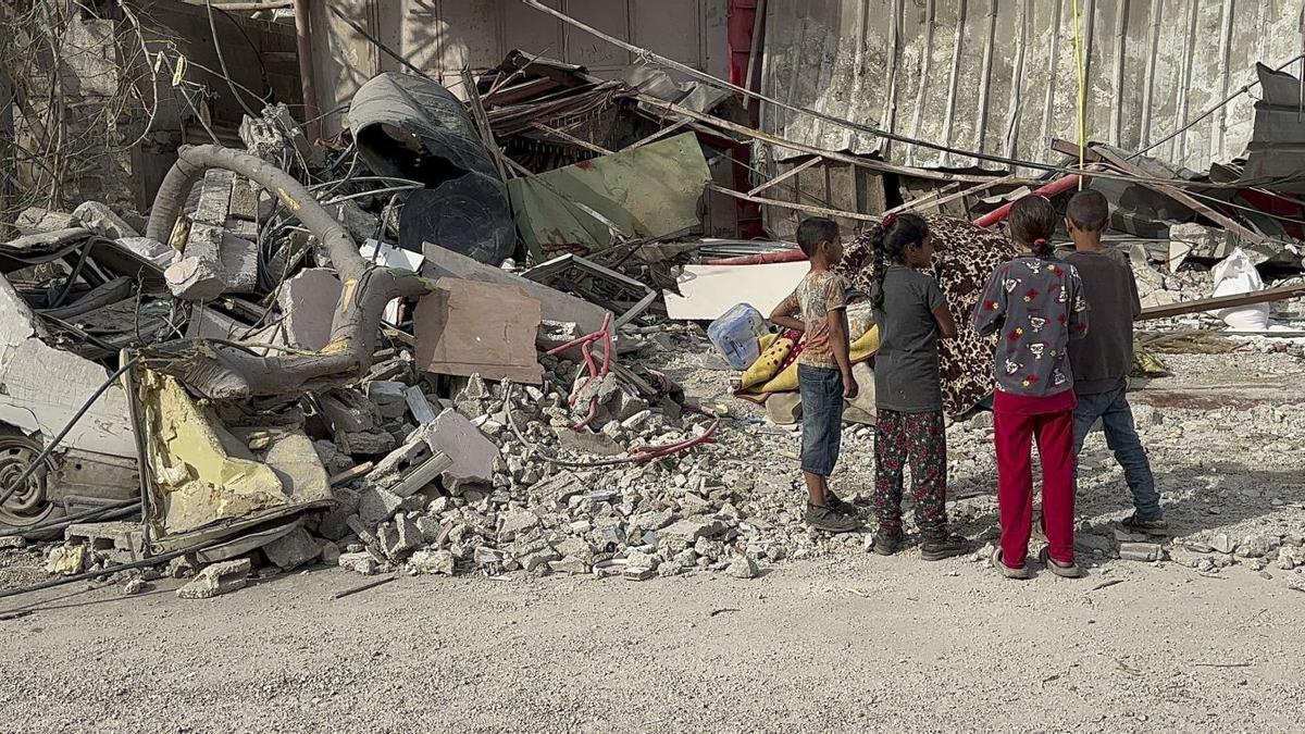 Cuatro niños palestinos observan el estado de un edificio destruido por los ataques en Gaza.