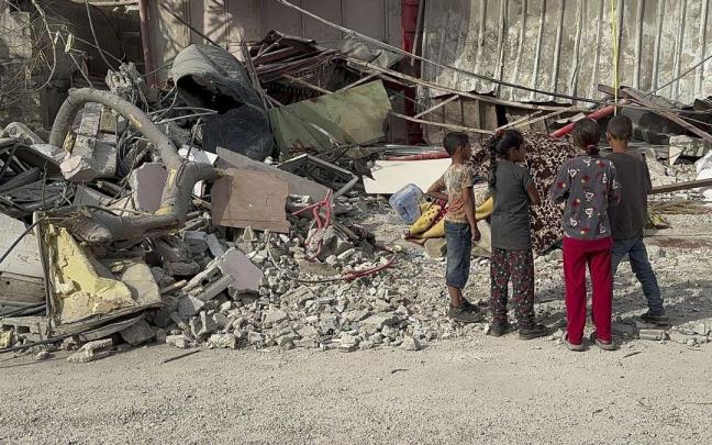 Cuatro niños palestinos observan el estado de un edificio destruido por los ataques en Gaza.