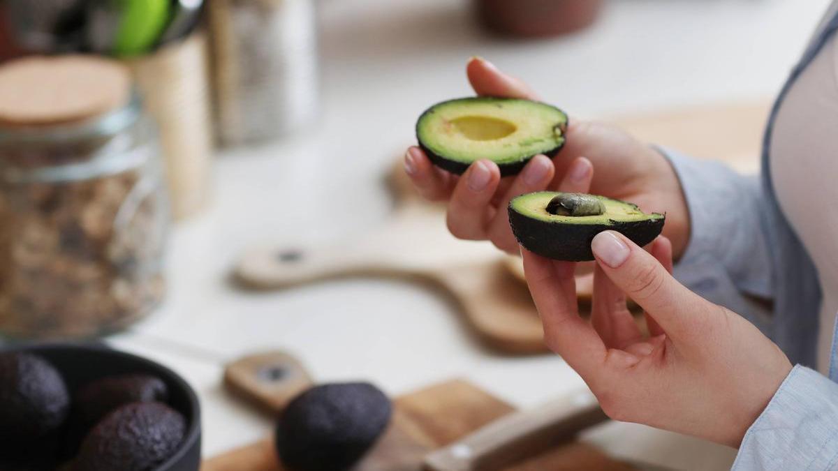 Manos de una chica abriendo un aguacate y comprobando su estado