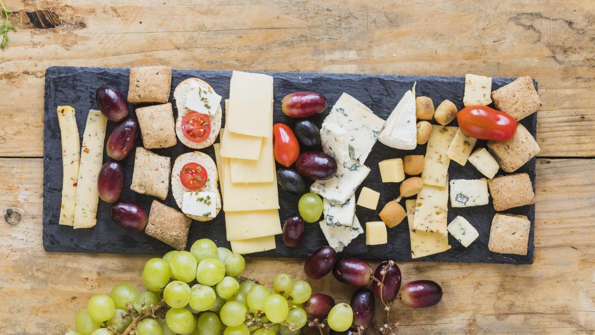 Tabla de quesos y embutidos, combinada con panes y frutas.