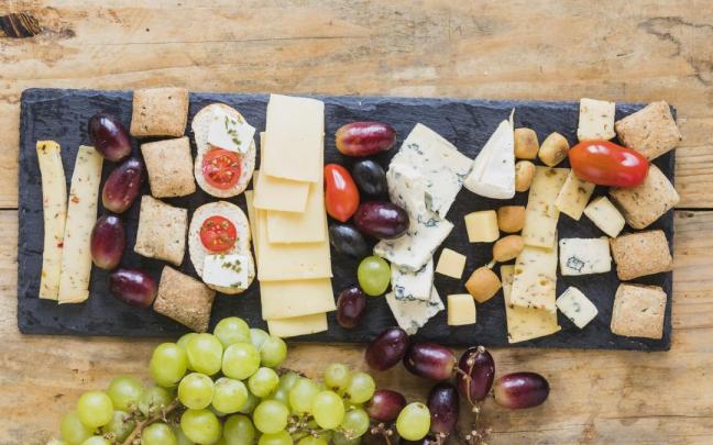 Tabla de quesos y embutidos, combinada con panes y frutas.