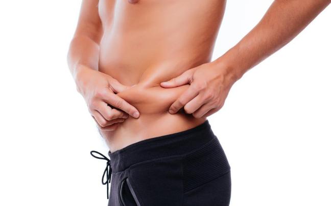 Un hombre marca con sus manos una lorza de grasa en la cintura.