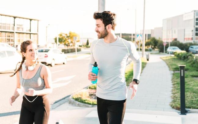 Un hombre sostiene una botella mientras corre junto a una mujer. Un hombre sostiene una botella mientras corre junto a una mujer.
