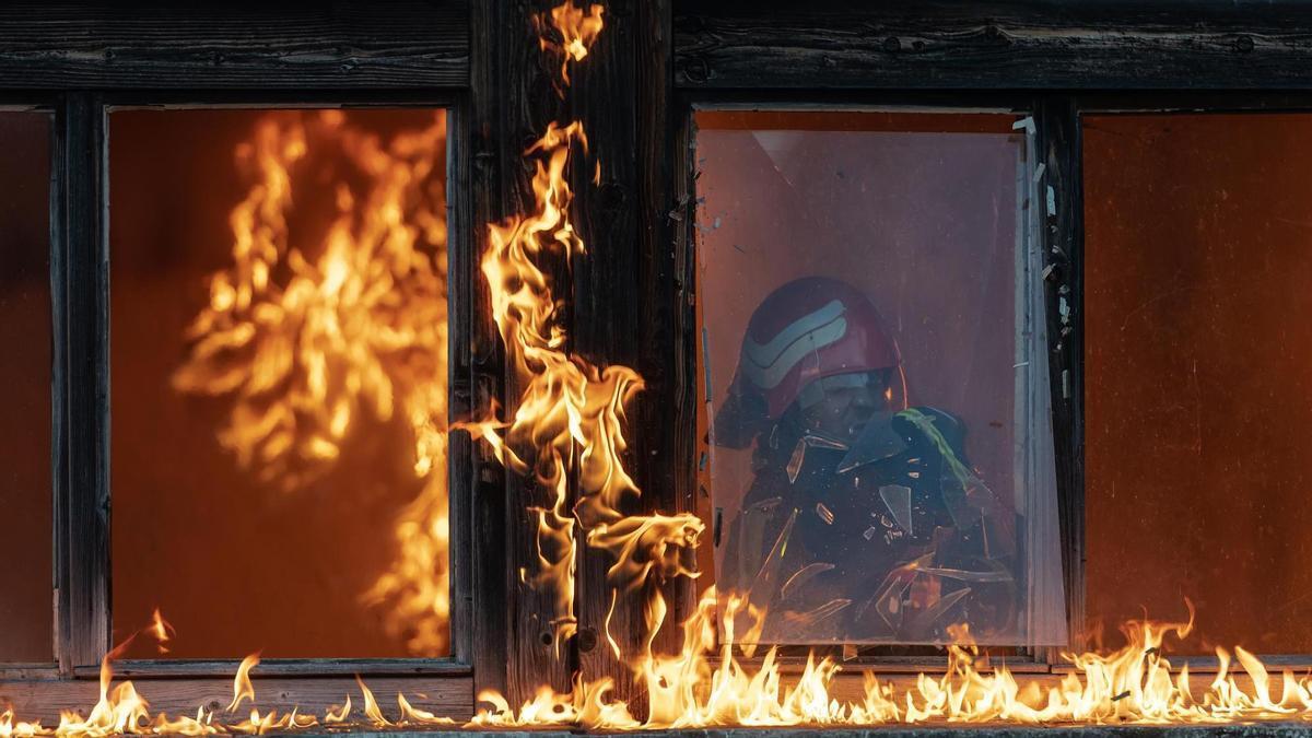 Un bombero trabaja en el interior de una vivienda en llamas.