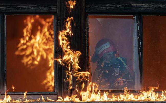 Un bombero trabaja en el interior de una vivienda en llamas.