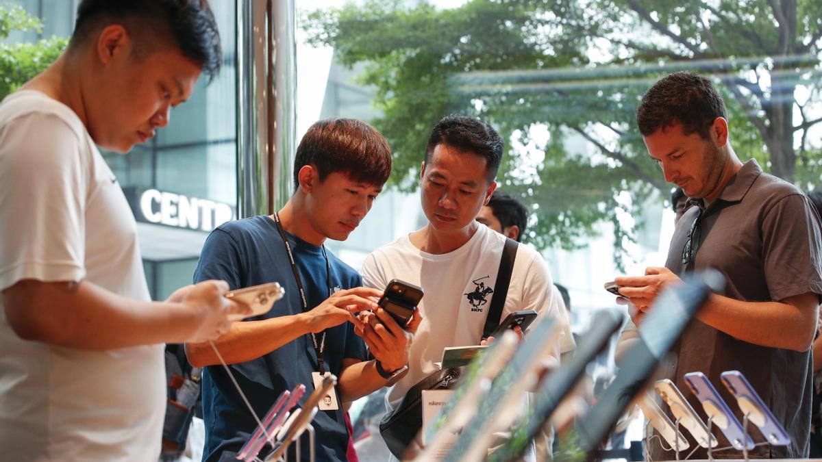 Un grupo de personas observa los nuevos iPhone 16 en una tienda de Bangkok.