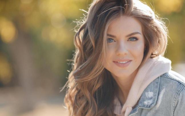 Una joven luce una estilosa melena rubia ondulada.
