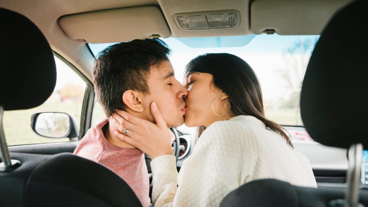 Una pareja se besa en el interior del un coche.