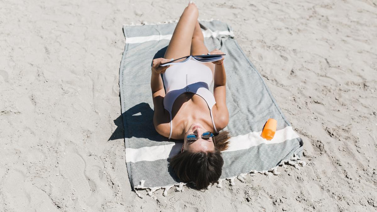 Una persona toma el sol en la playa.