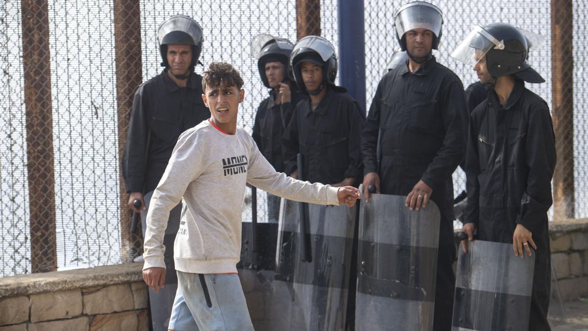 Un joven pasa frente a miembros de las fuerzas de seguridad de Marruecos.