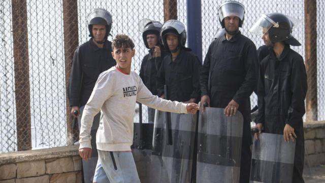 Un joven pasa frente a miembros de las fuerzas de seguridad de Marruecos.