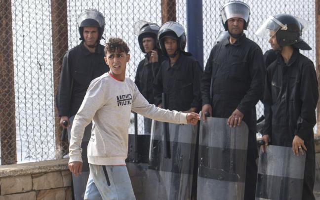 Un joven pasa frente a miembros de las fuerzas de seguridad de Marruecos.
