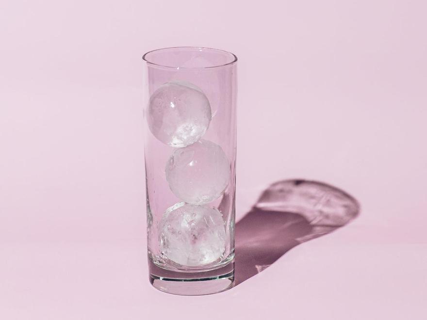 Un vaso con tres cubitos de hielo en forma de esfera.