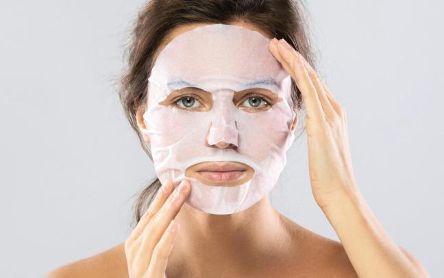 Una mujer se coloca una mascarilla facial.