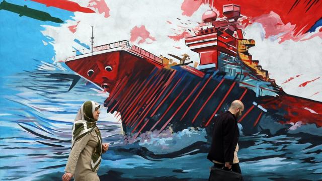 Iraníes pasan junto a un mural contra EE.UU. e Israel en una calle de Teherán