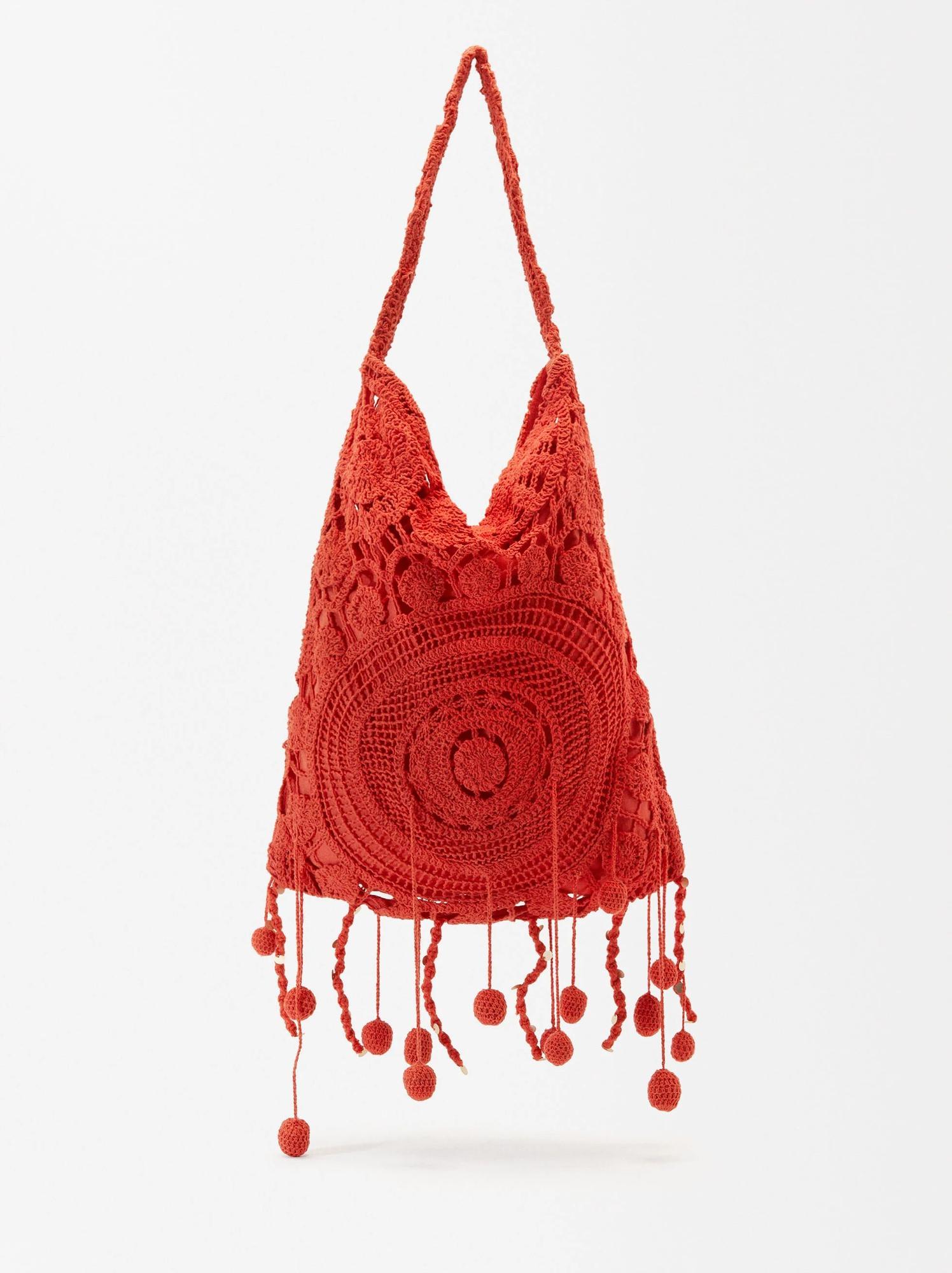 Bolso rojo de ganchillo con divertidos colgantes.
