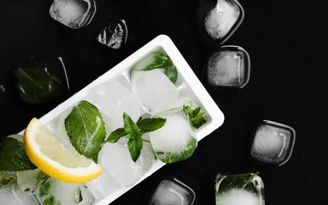 Cubitera de hielo con cubitos a su alrededor.