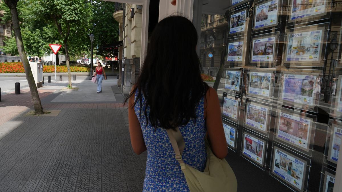 Una joven contempla las ofertas expuestas en una inmobiliaria en Bilbao.