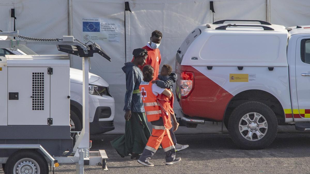 Agentes de los Servicios de Emergencias atienden a una mujer y un menor a su llegada al Puerto de la Restinga